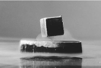 A magnet is hovering over a superconductor, demonstrating that magnetic fields cannot penetrate the superconductor, known as the Meissner effect.